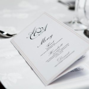 Close-up of a refined dining table with menu and silverware, showcasing elegance in a formal restaurant setting.